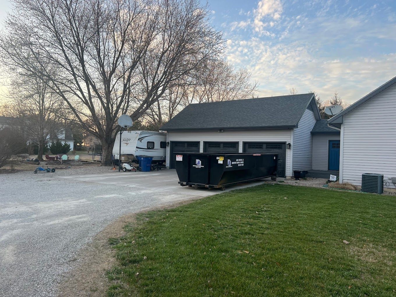 A house with a dumpster in front of it and a garage.