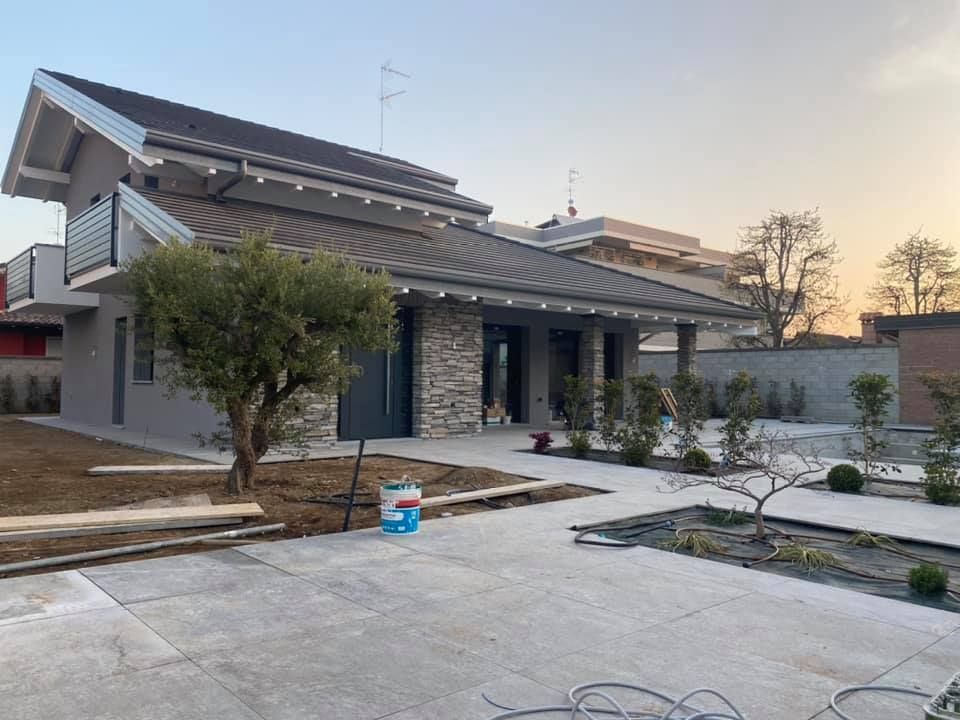 Casa moderna con esterni grigi, facciata in pietra e giardino paesaggistico.