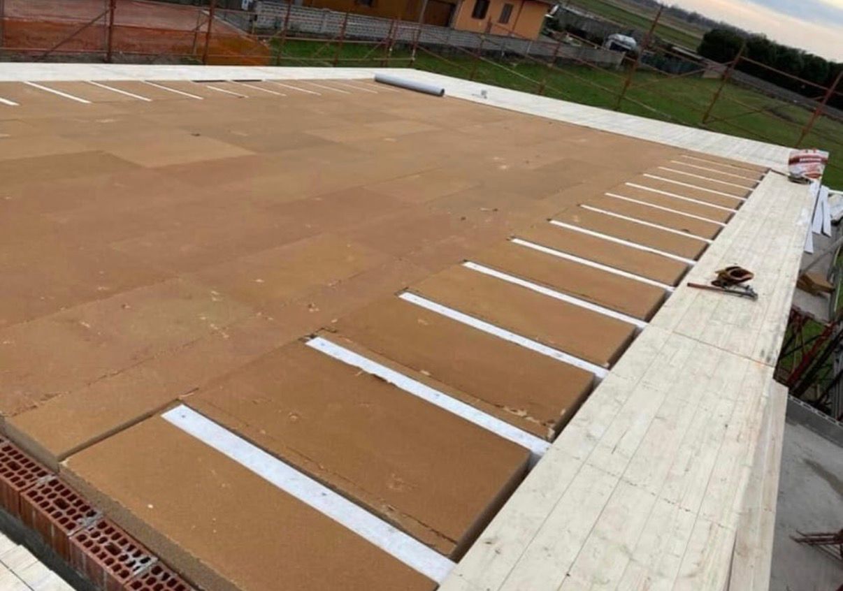 Uomo su un tetto che indica. Il tetto è fatto di assi di legno e materiale marrone. Sullo sfondo si vedono degli edifici.