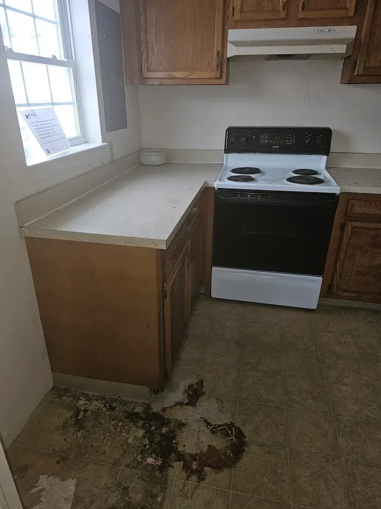 A kitchen with a stove and a dirty floor.