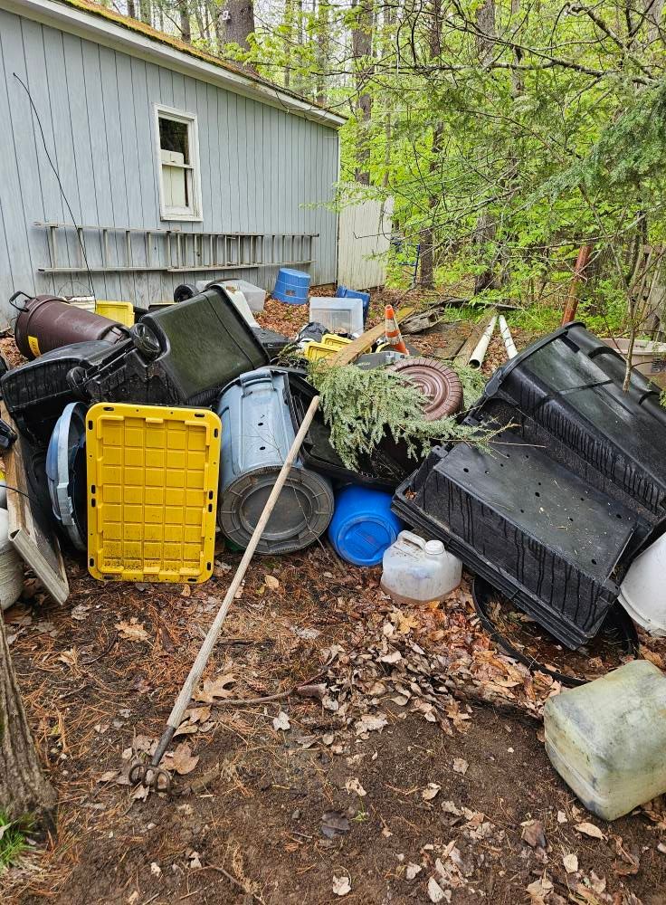 A pile of trash is sitting on the ground in front of a house.