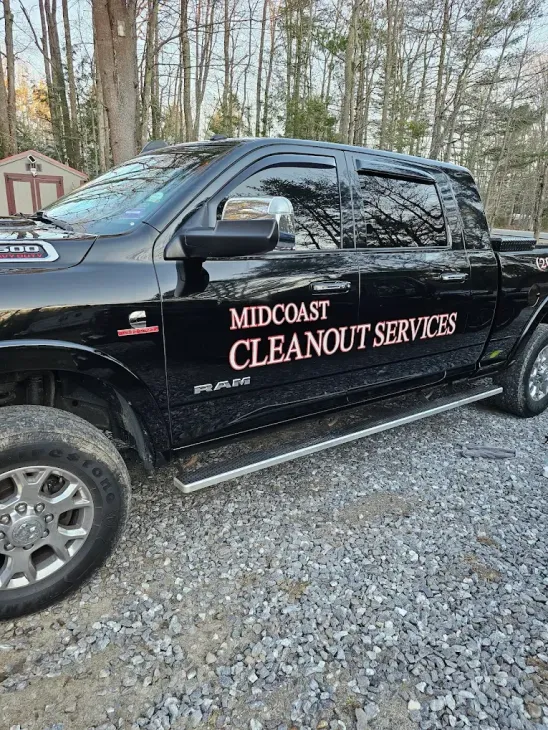 A black truck is parked in a gravel lot.