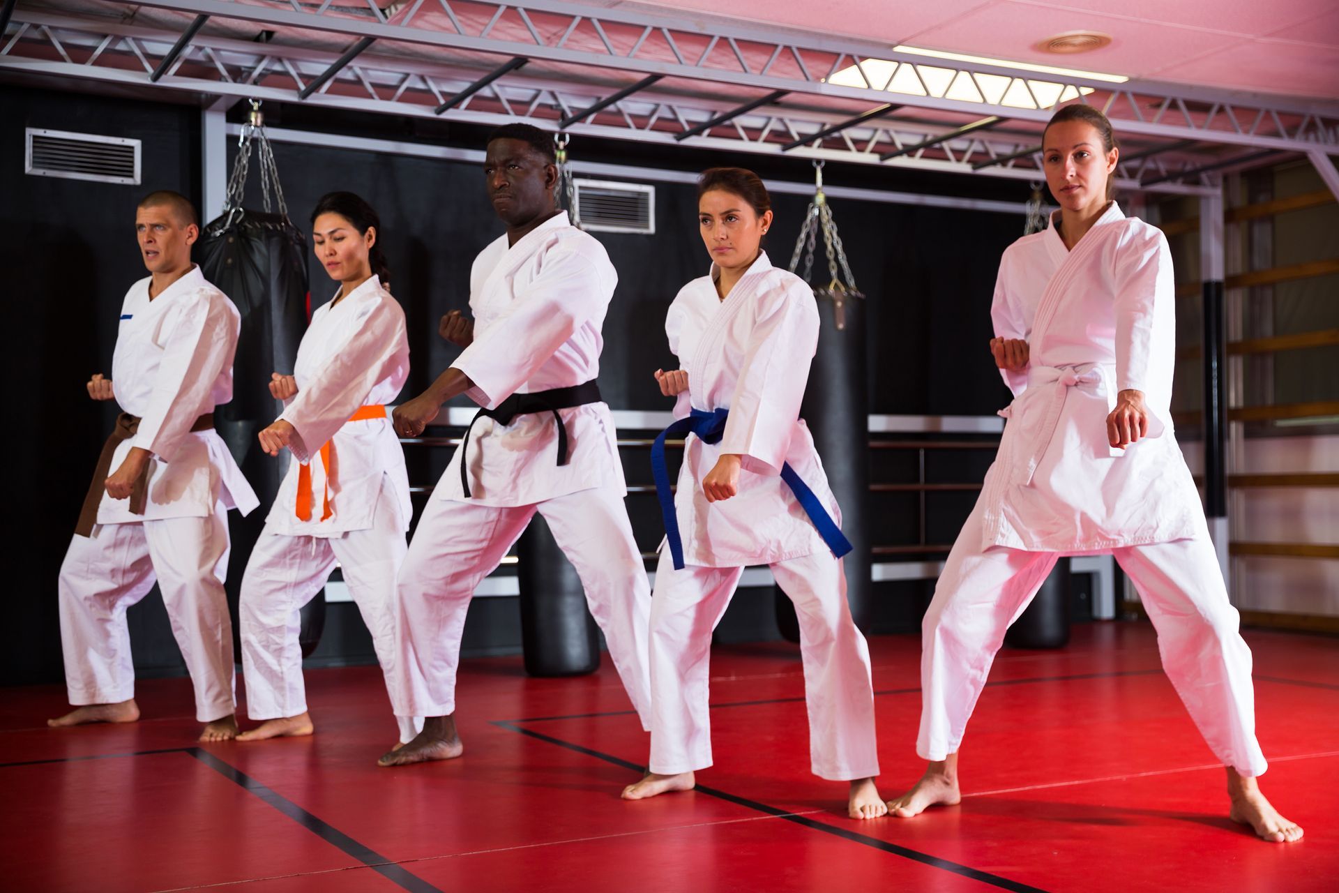 A group of people are practicing karate in a gym.