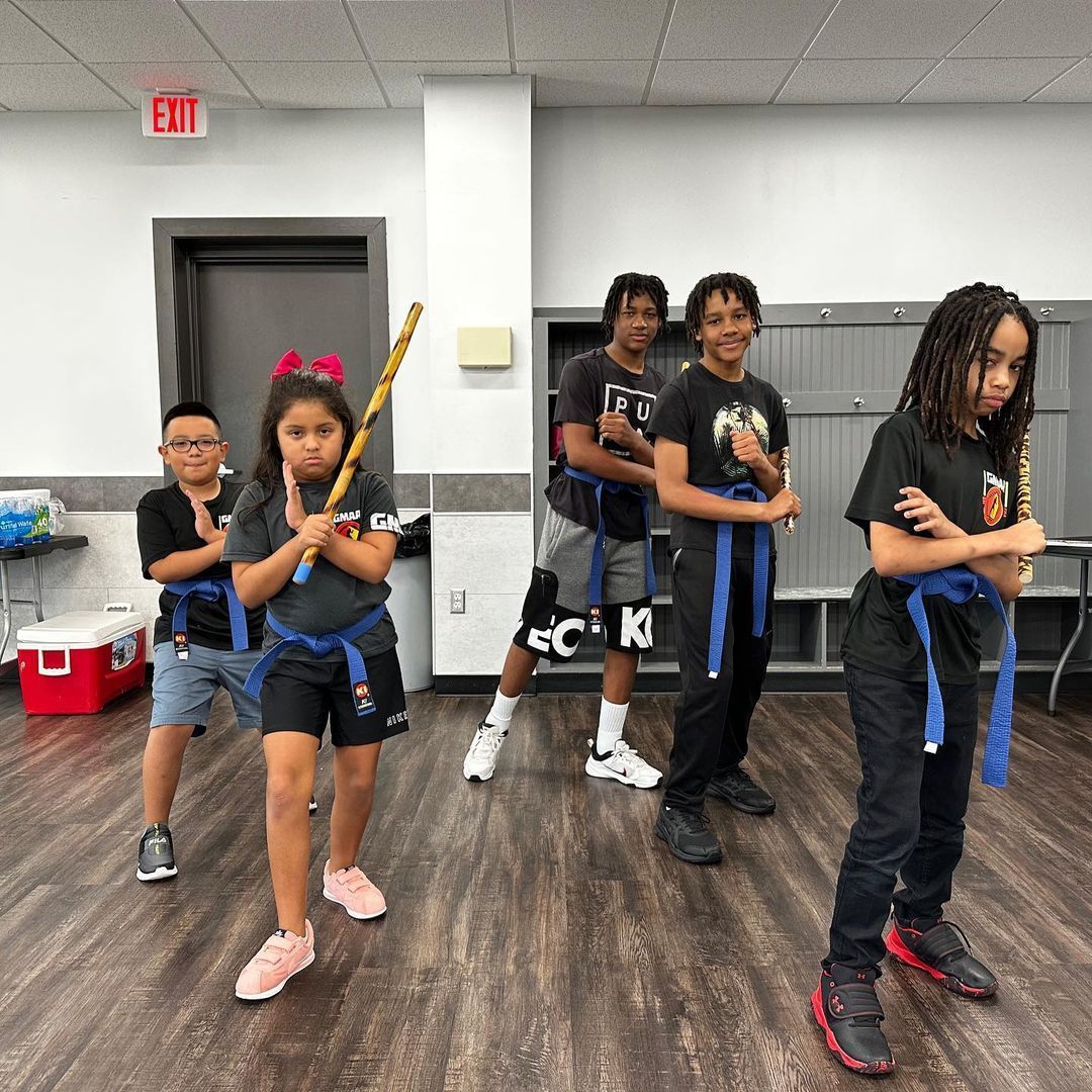 A group of children are standing in a room holding bats.