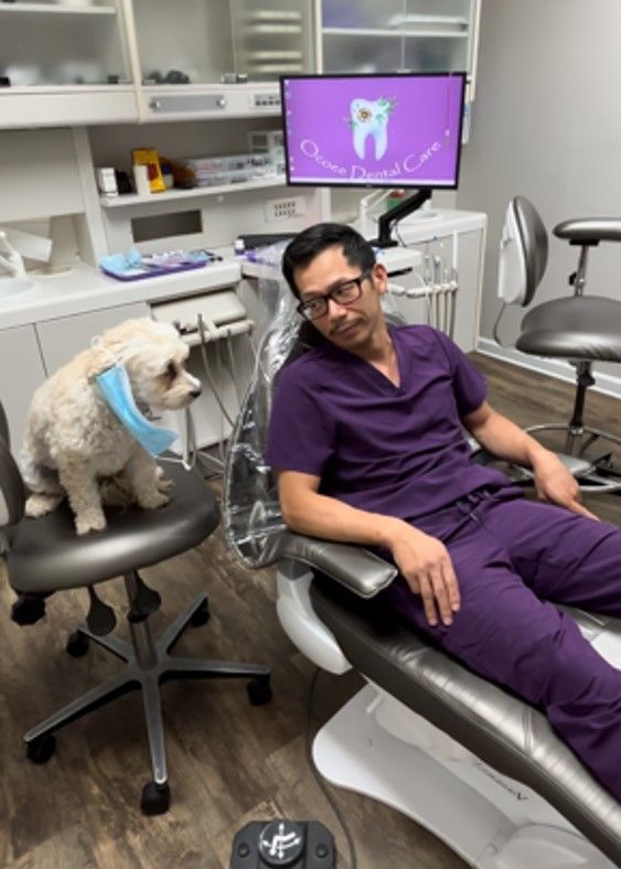 Dr. Ta is sitting in a dental chair with Watson beside him.