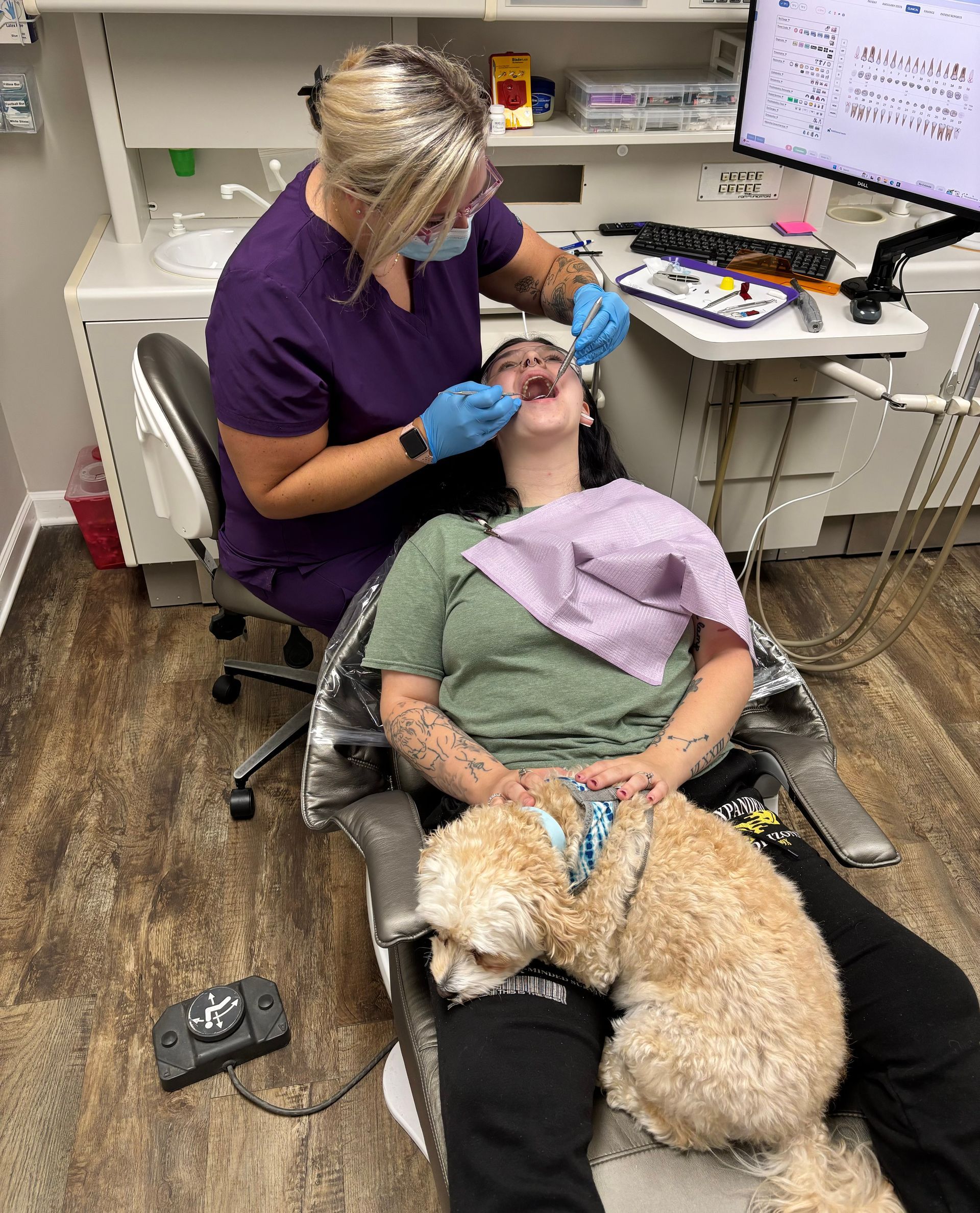 A woman is sitting in a dental chair with a dental anxiety dog.