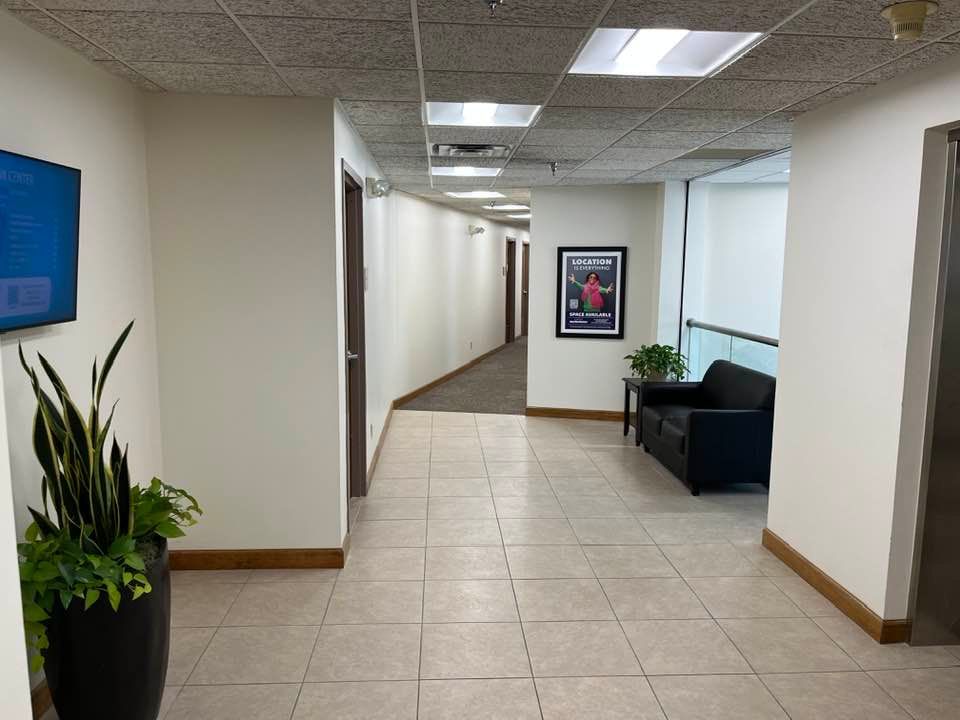 A long hallway with a couch and a potted plant.
