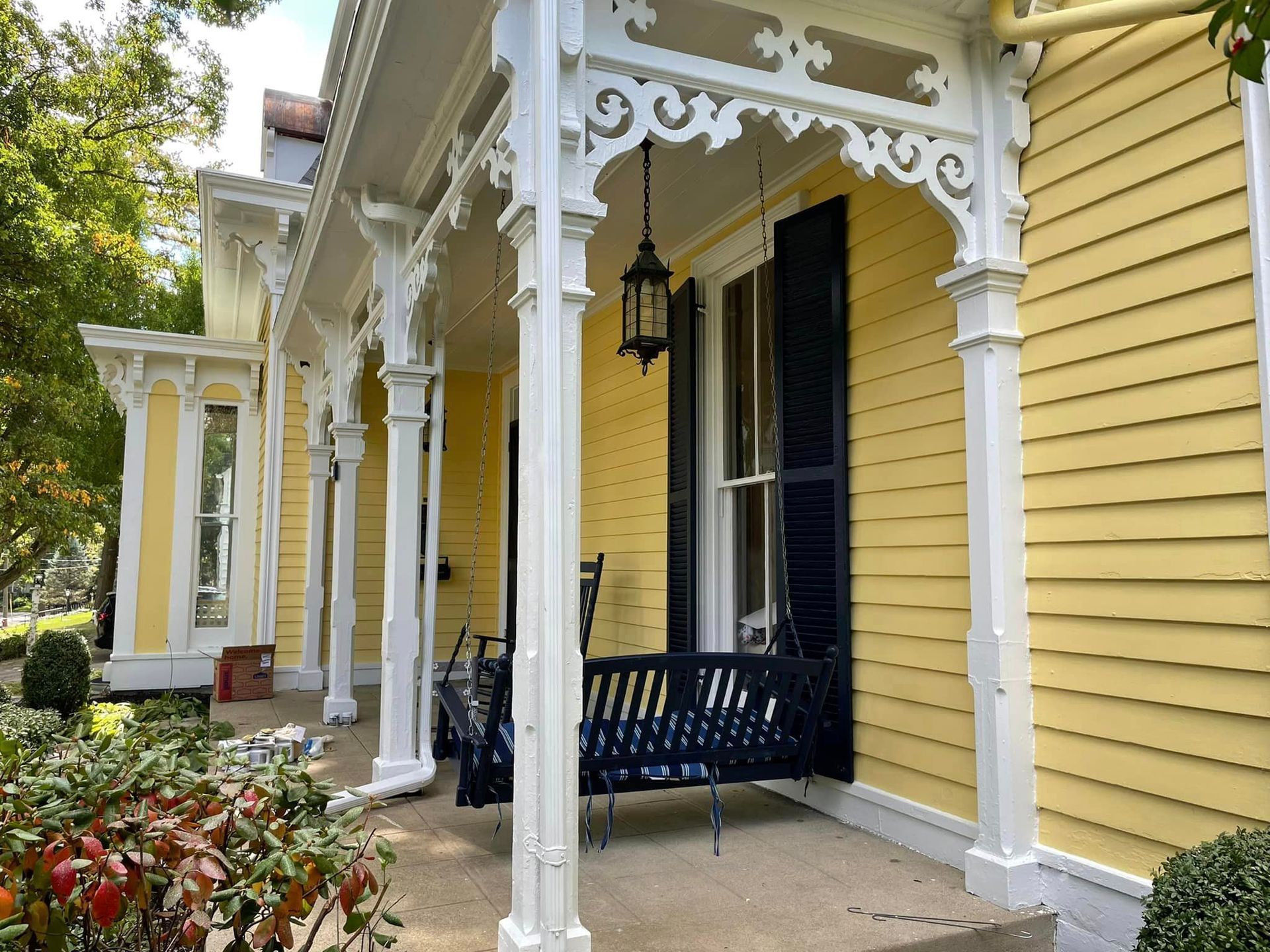 A yellow house with a porch with a swing on it