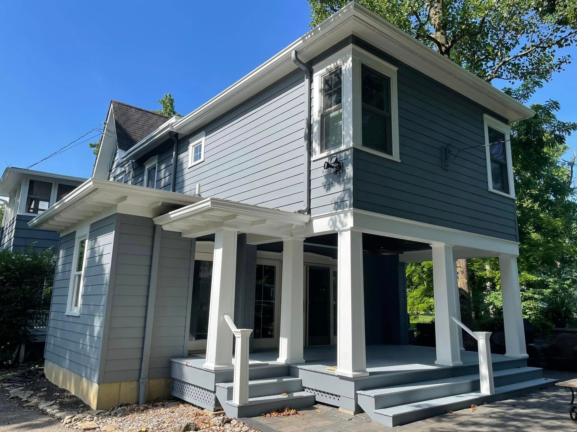 A small gray house with a white porch and stairs.