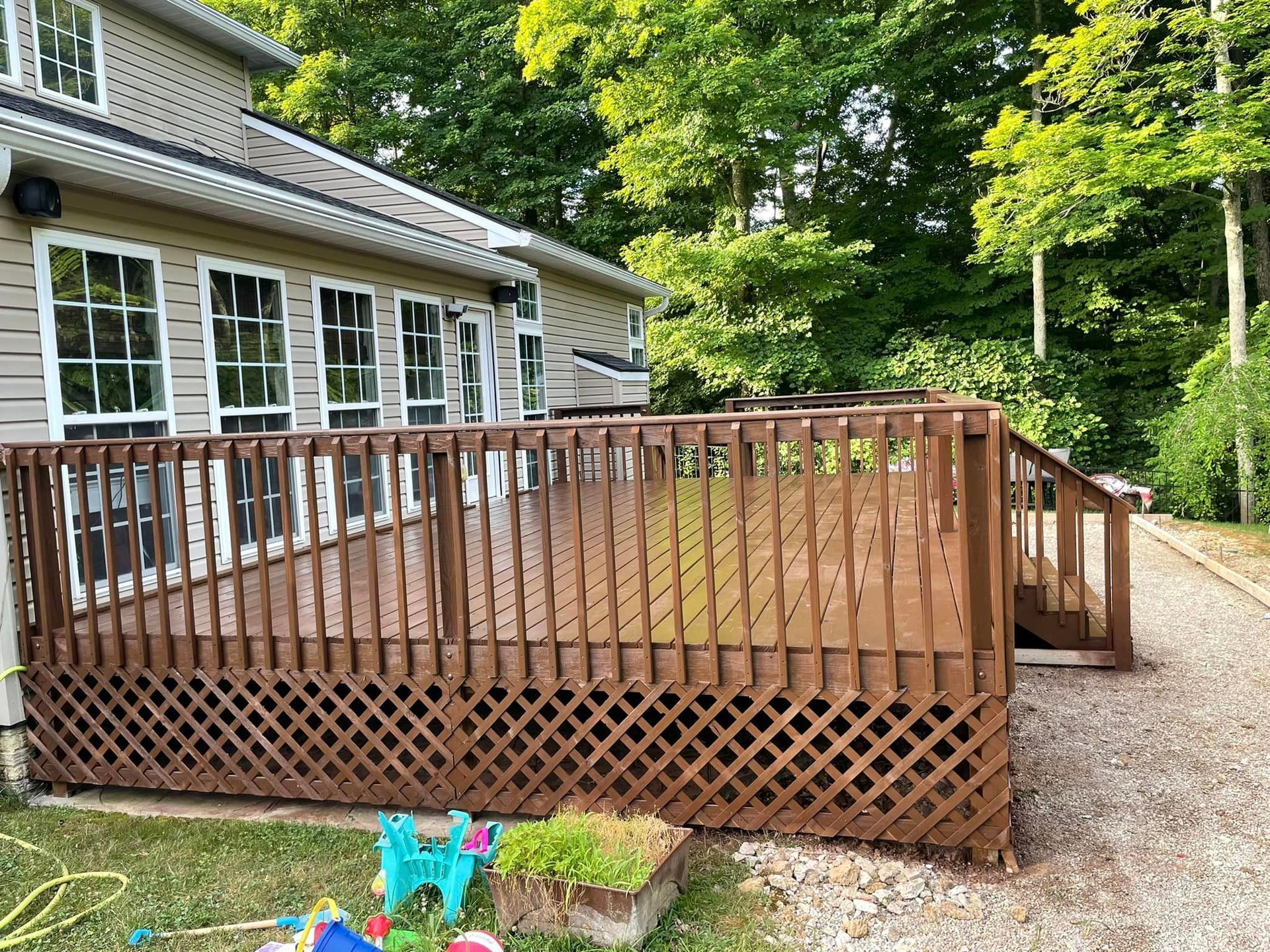 A large wooden deck is sitting in front of a house.