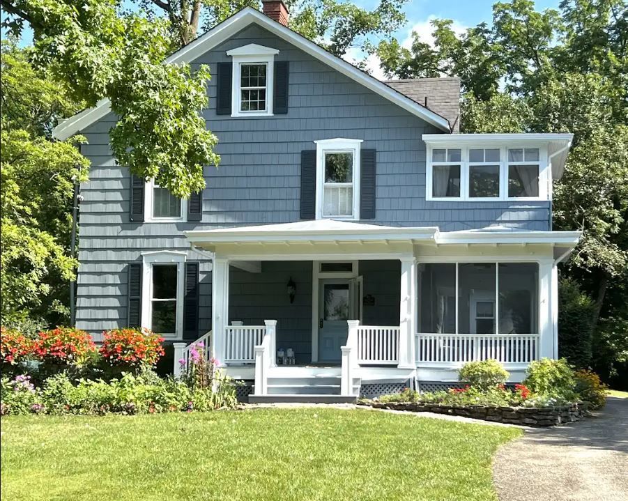 A blue barn with white doors is in the middle of a grassy field.