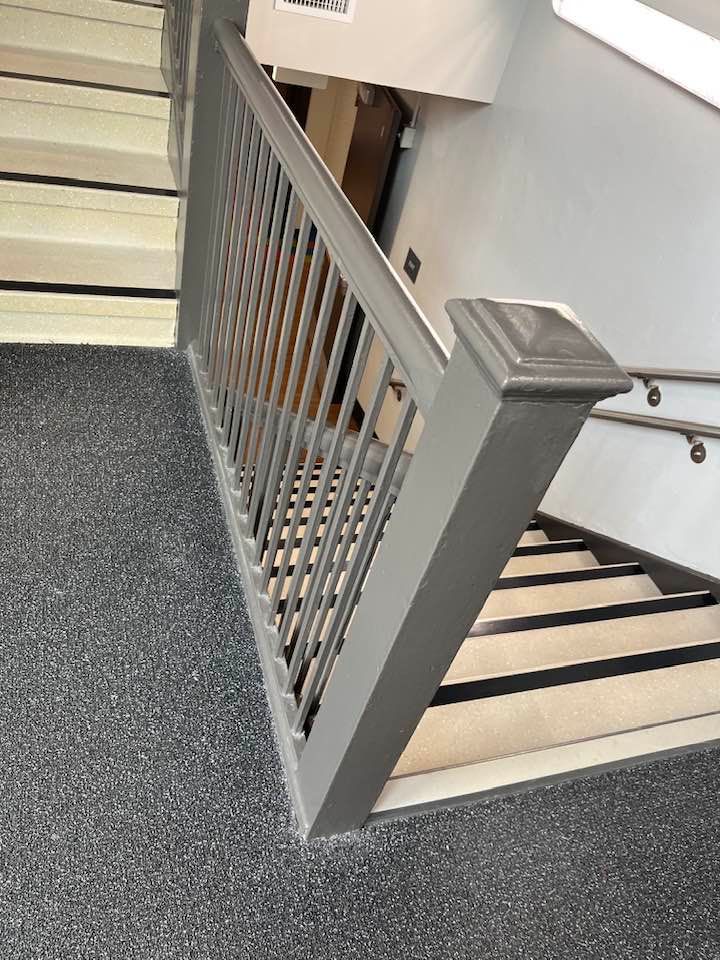 A staircase with a metal railing and a carpeted floor.