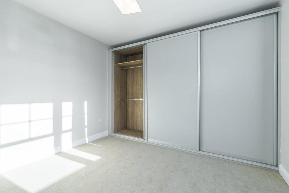 An Empty Bedroom with A Large Sliding Wardrobe and A Window — Bestbuy Kitchens in Yandina, QLD