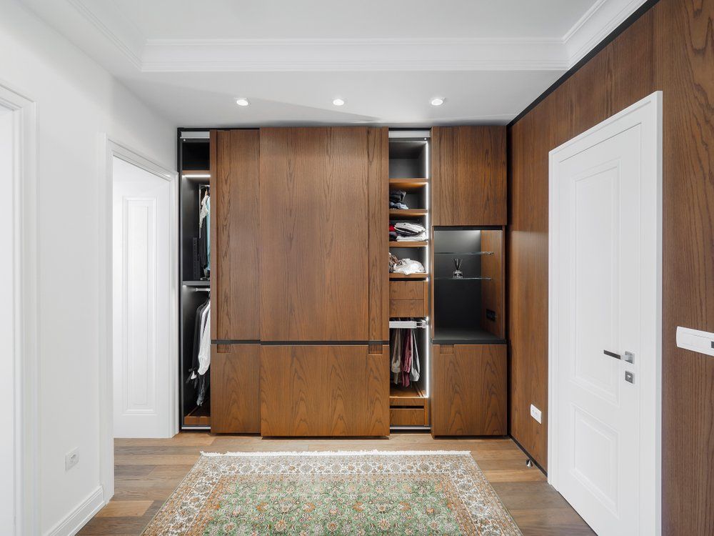 A Walk in Closet with Sliding Wooden Doors and A Rug — Bestbuy Kitchens in Yandina, QLD