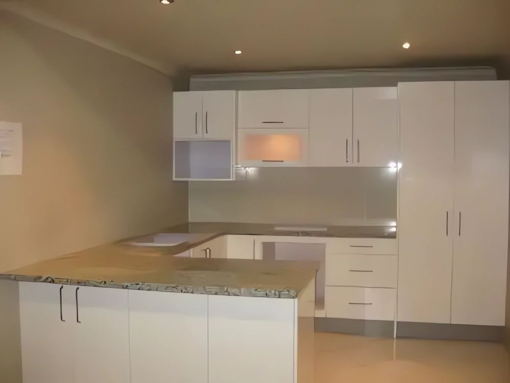 An Empty Kitchen with White Cabinets and Granite Counter Tops — Bestbuy Kitchens in Yandina, QLD