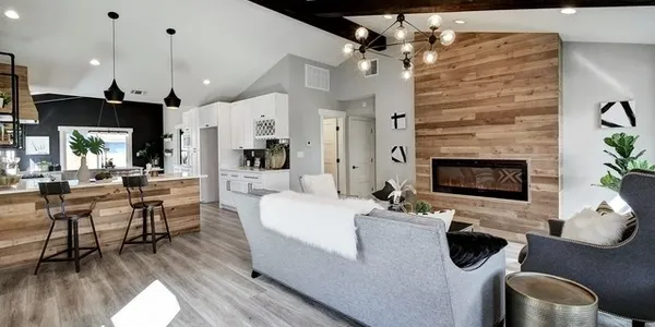 Modern living room with fireplace, kitchen island, and gray furnishings.