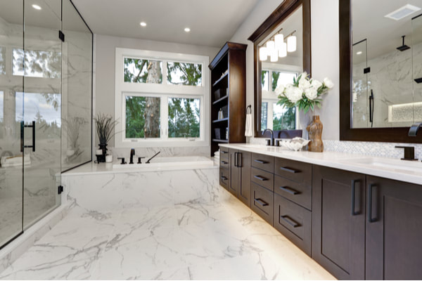 Modern bathroom with marble floors, a window over a bathtub, and dark brown cabinets.