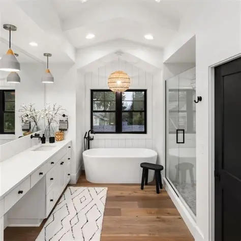 Bright, modern bathroom with a tub, shower, and vanity. White walls, wood floor, and black accents.