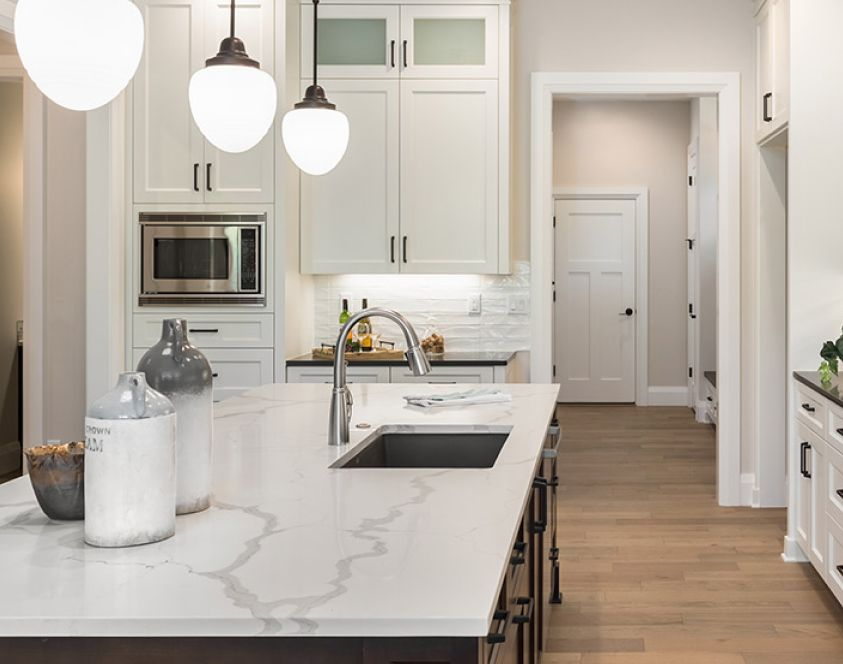 Modern kitchen with white cabinets, marble island, and pendant lights.