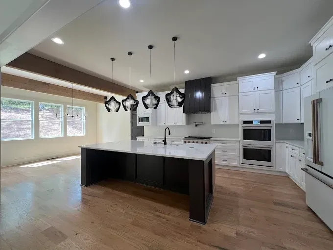 Modern kitchen with white cabinets, dark island, and pendant lights.