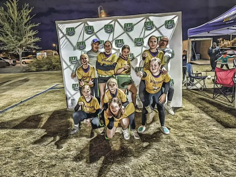 Youth sports team posing in front of a banner at an outdoor night event