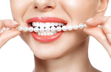 woman holding pearls up to her teeth