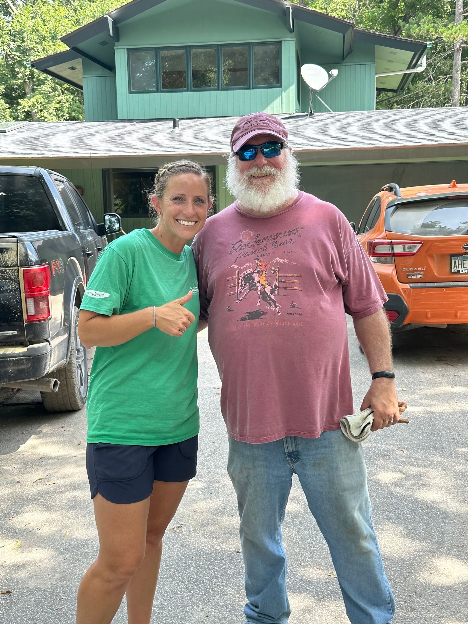 A man and a woman are posing for a picture in front of a house.