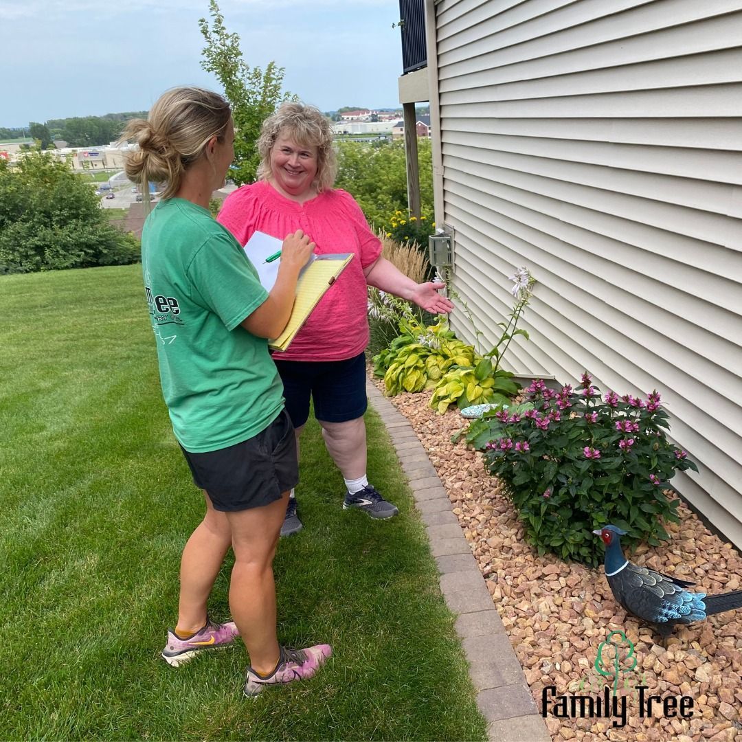 Two women are standing in front of a house talking to each other.