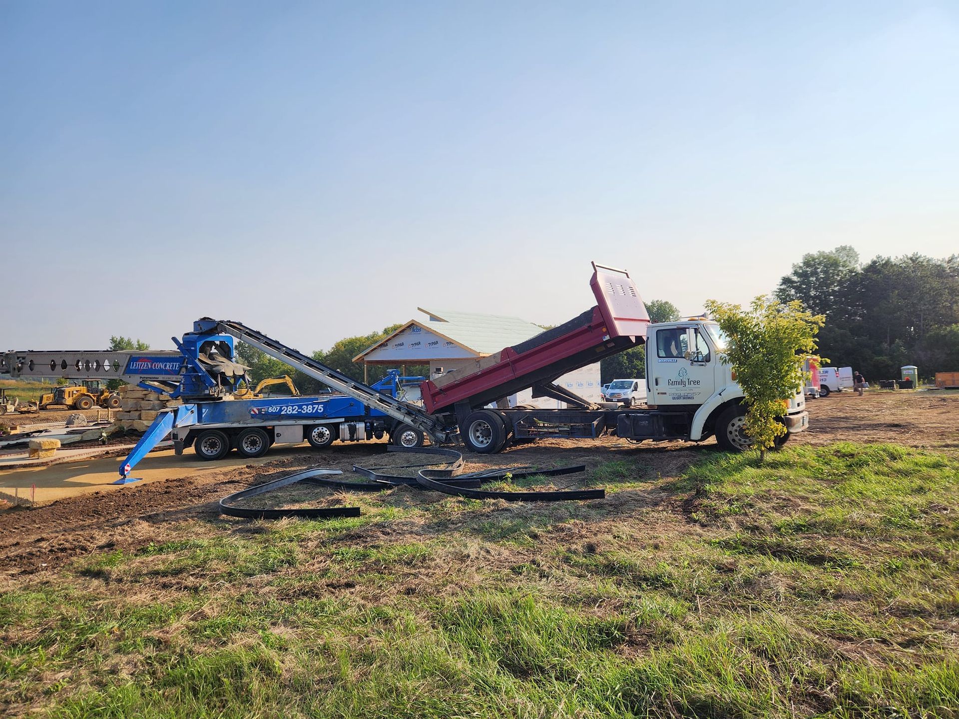 A dump truck is being towed by a crane in a field.