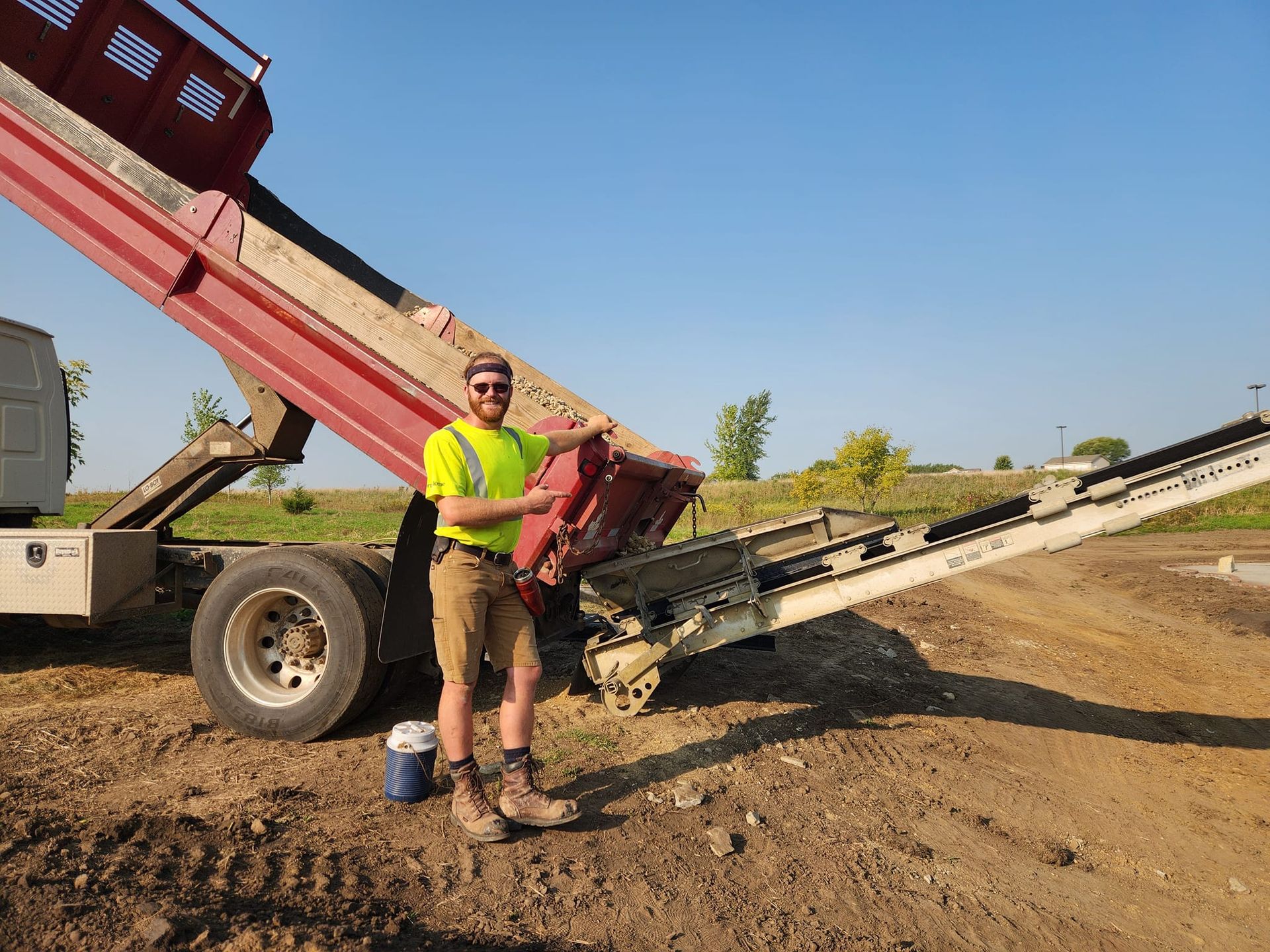 A man is standing in front of a dump truck.