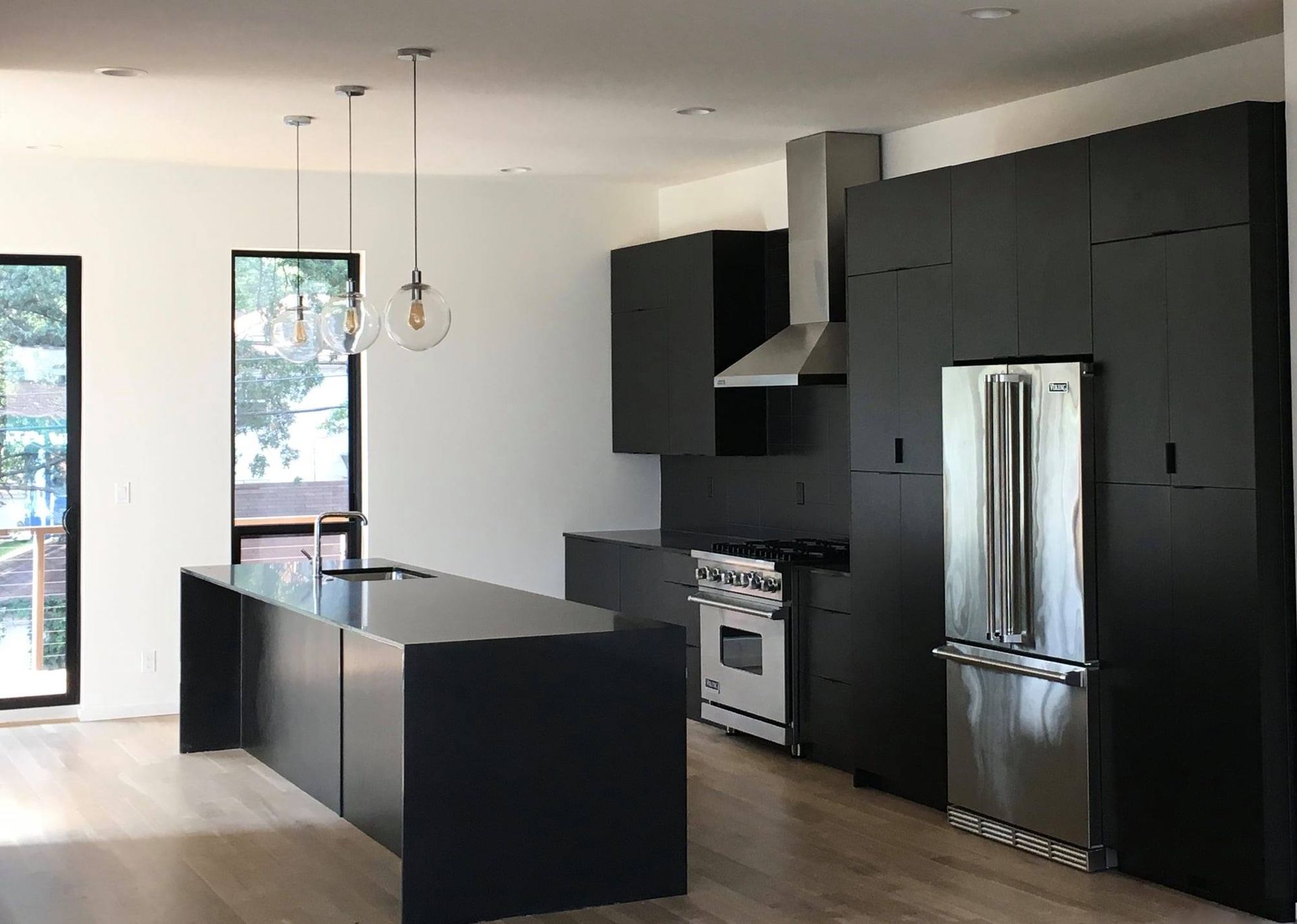 a kitchen remodel with black cabinets and a stainless steel refrigerator