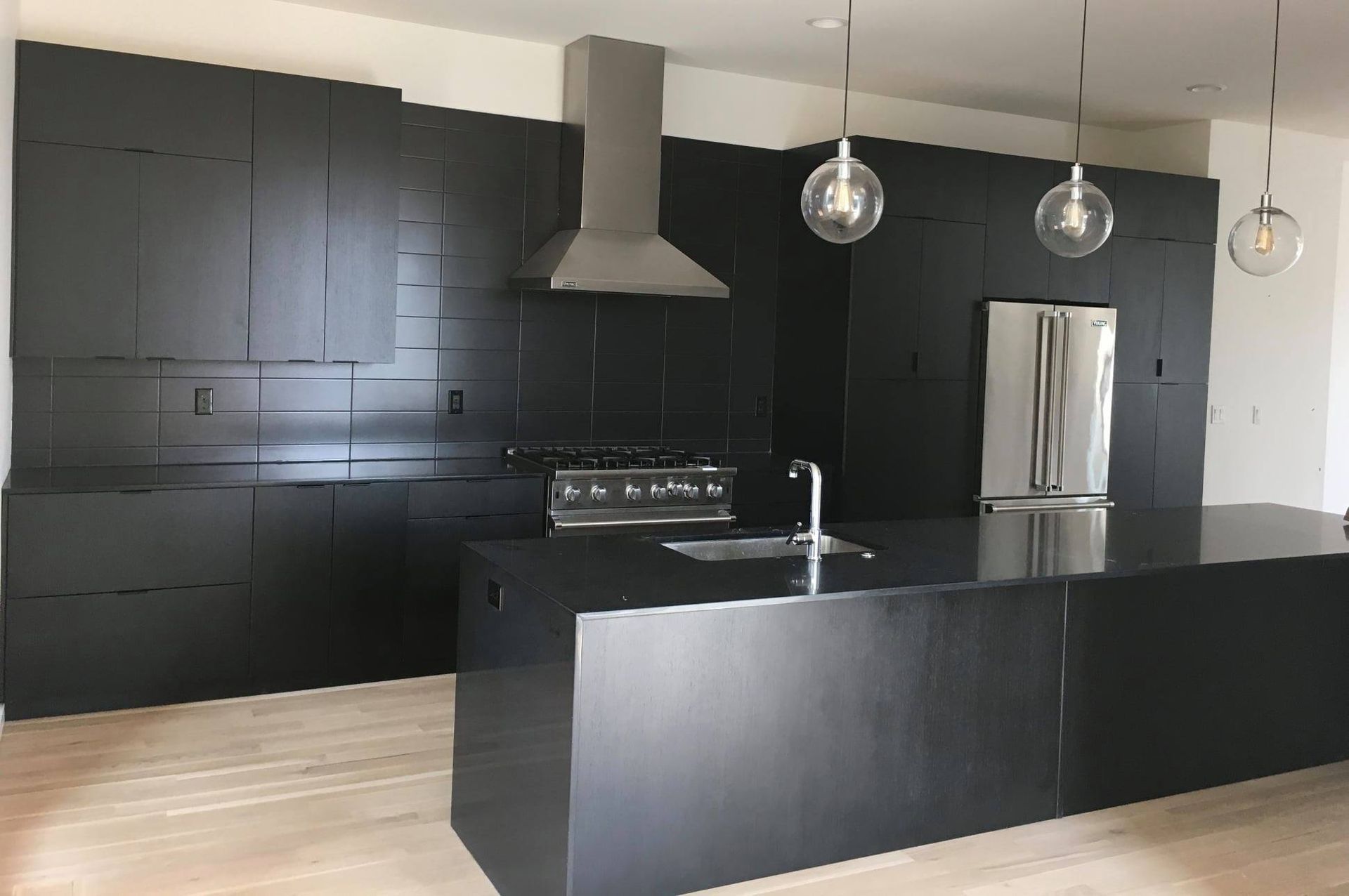 a kitchen remodel with black cabinets and a stainless steel refrigerator