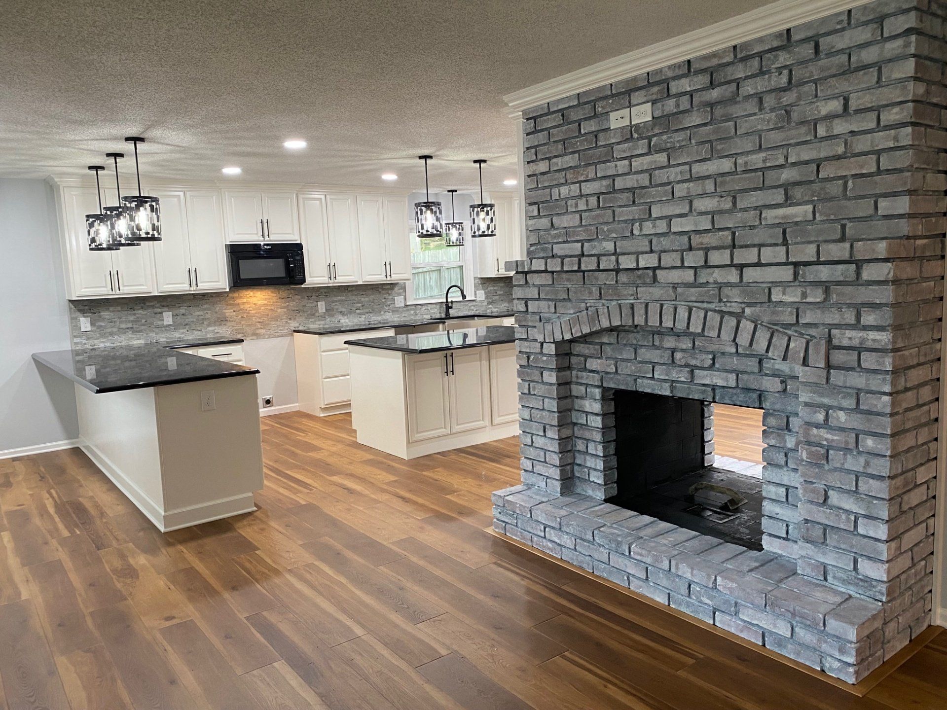 a kitchen remodel with white cabinets and a brick fireplace