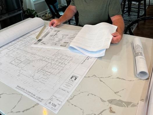 A man is sitting at a table looking at blueprints.