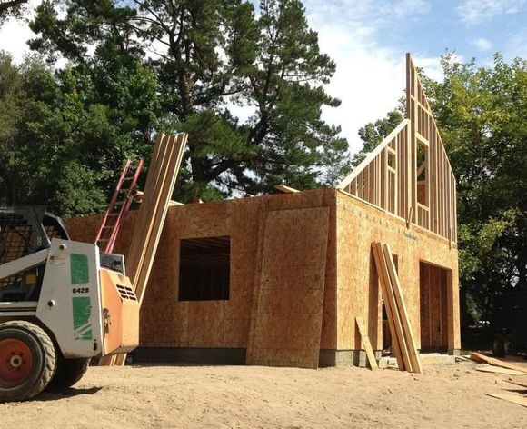 A bobcat is parked in front of a house under construction
