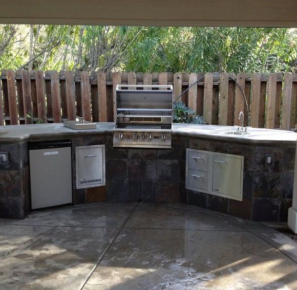An outdoor kitchen with a grill and a dishwasher