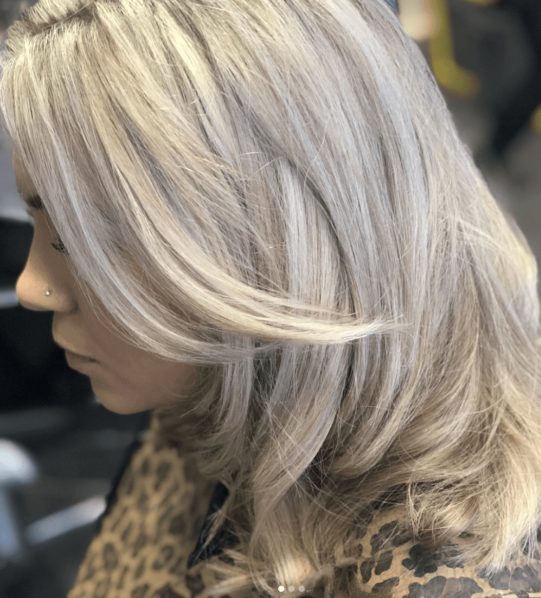 A woman with long blonde hair is wearing a leopard print shirt.