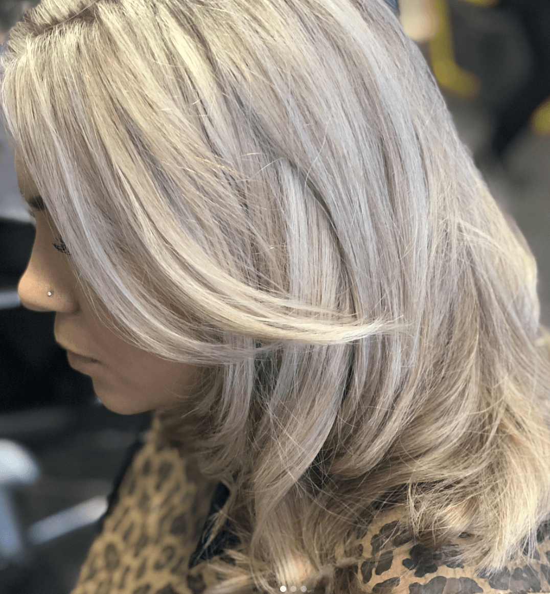 A woman with long blonde hair is wearing a leopard print shirt.