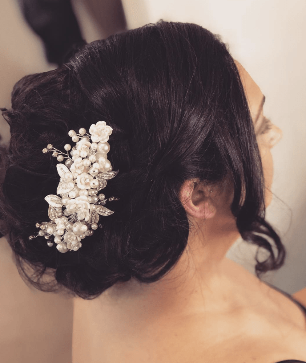 A woman with her hair in a bun has a pearl comb in her hair