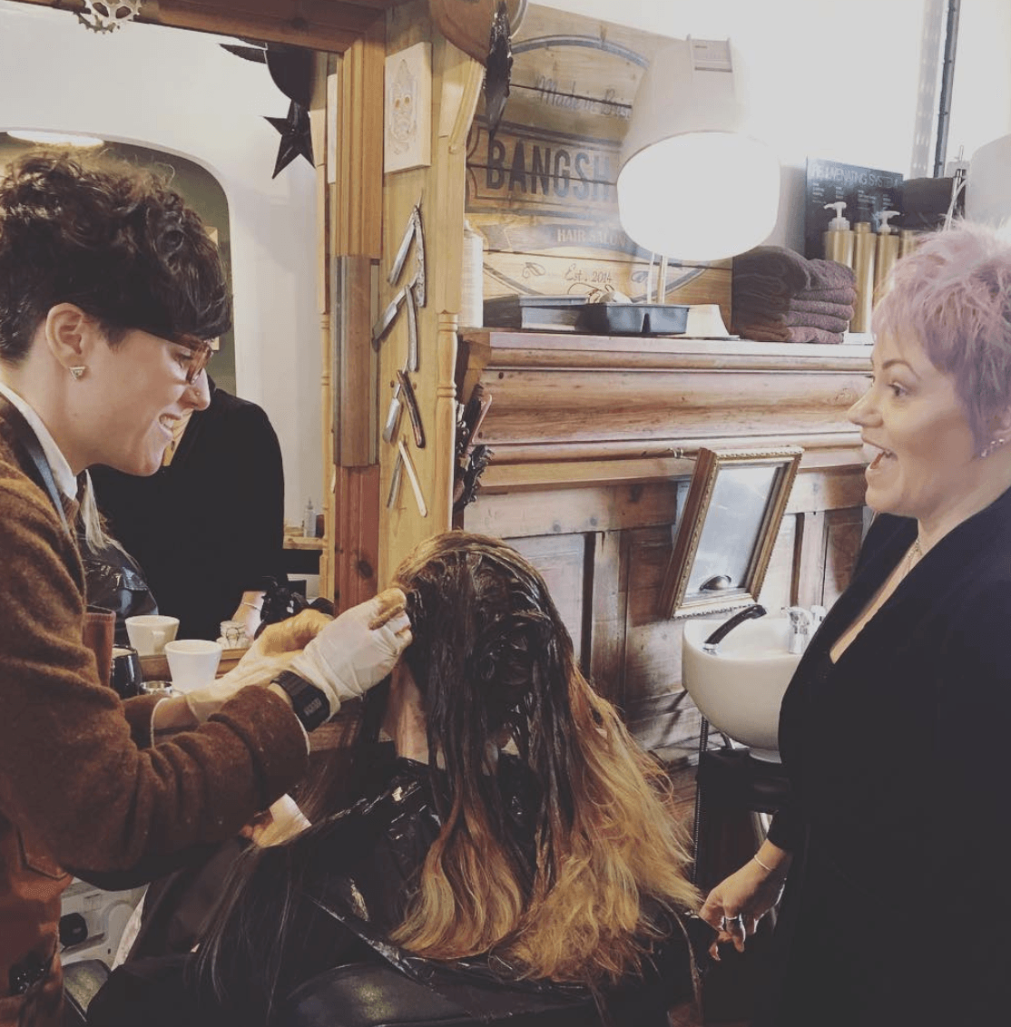A woman with pink hair is getting her hair dyed