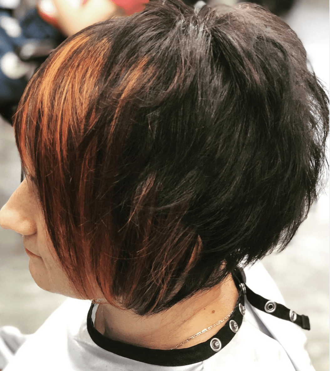 A woman with short hair has a black choker around her neck