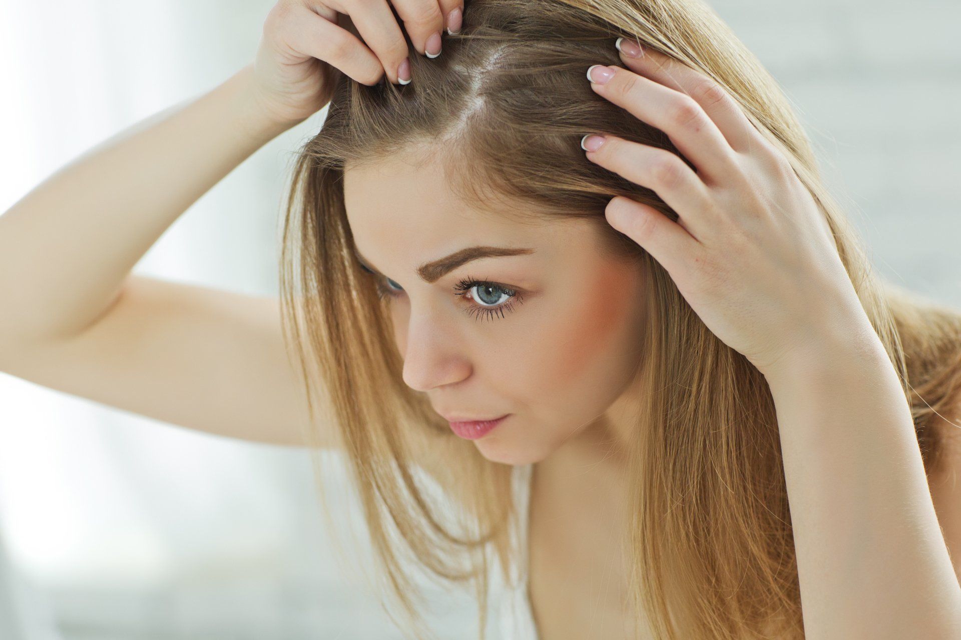 A woman is looking at her hair in the mirror.