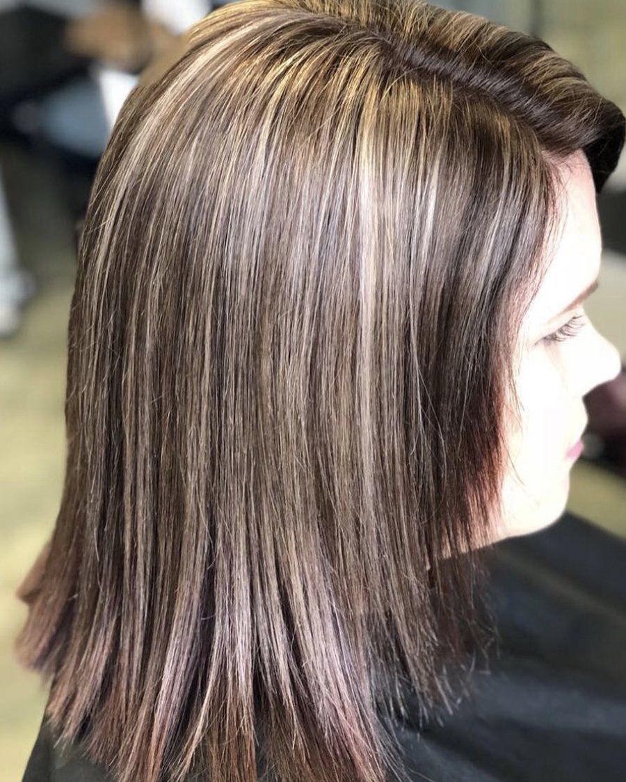 A woman with long brown hair is sitting in a chair in a salon.