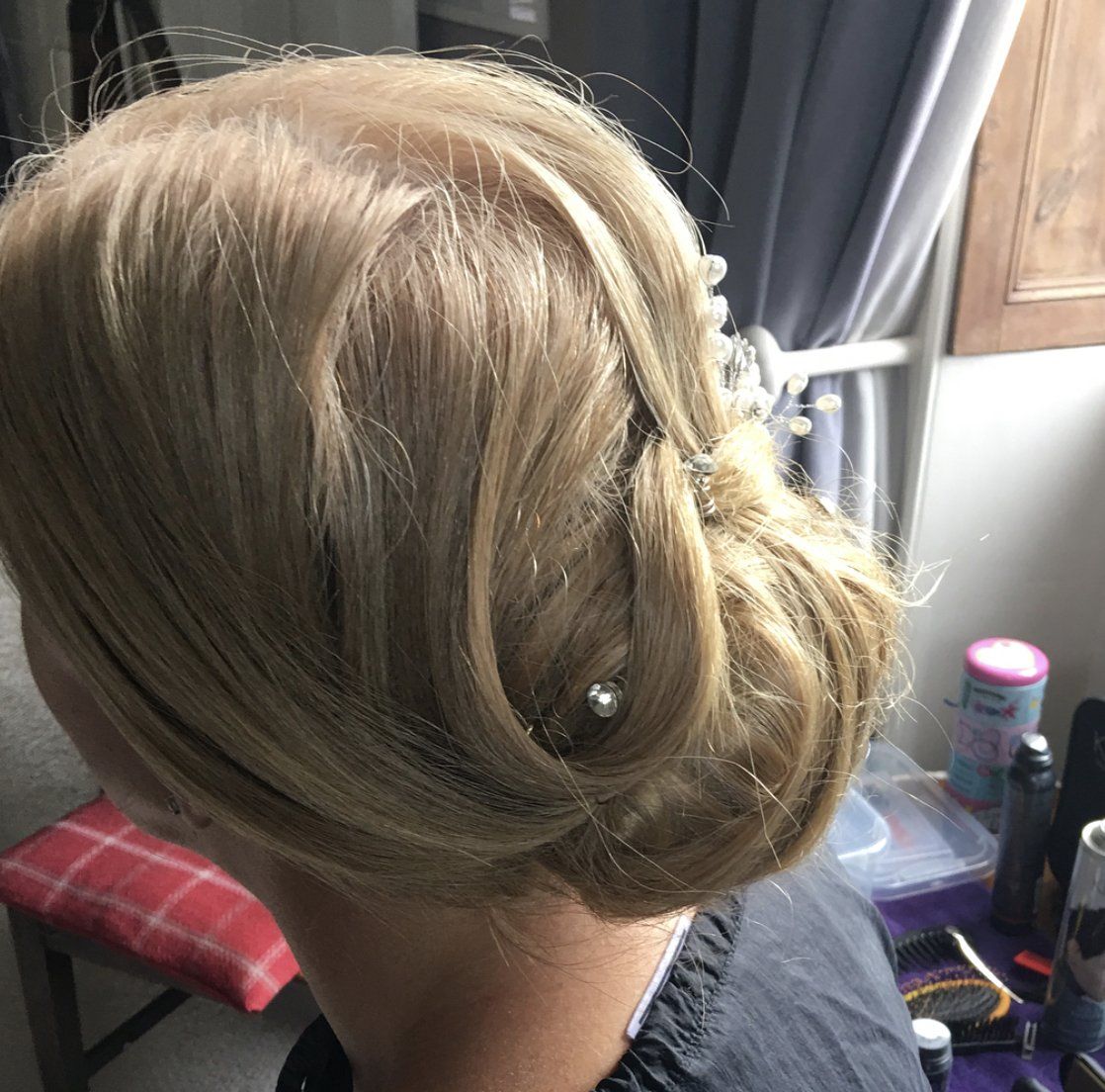 A woman with blonde hair in a bun is sitting in front of a window