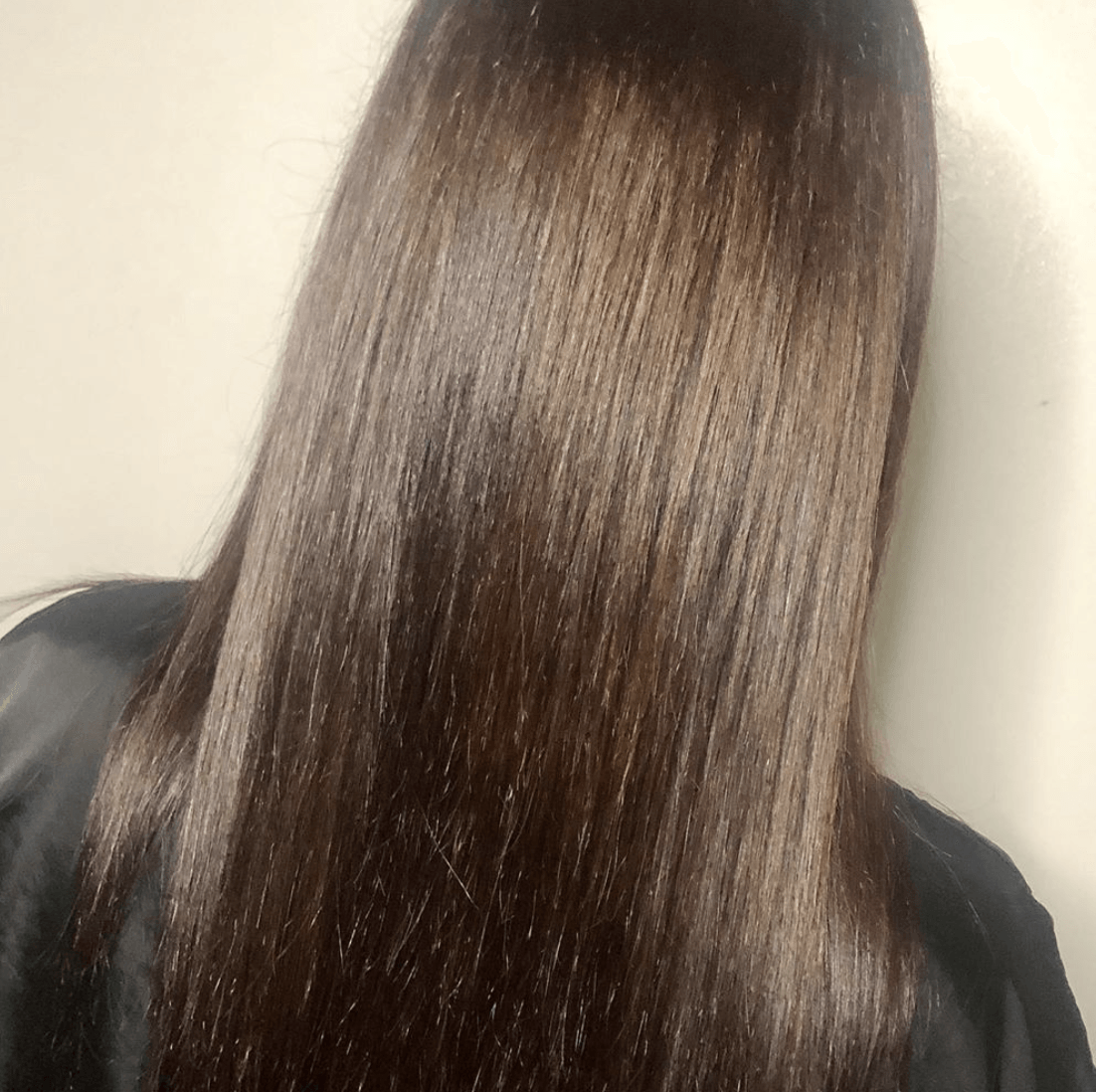 The back of a woman 's head with long straight brown hair.