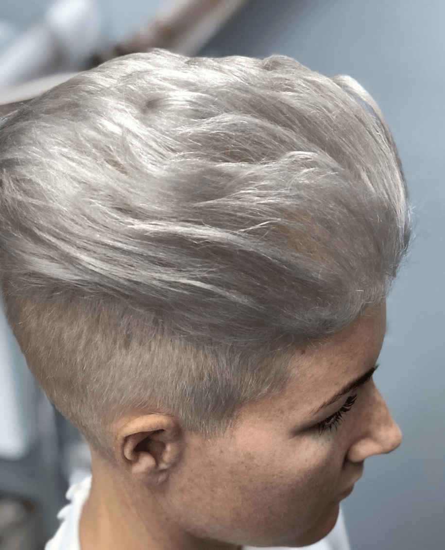 A woman with short blonde hair has a shaved head.