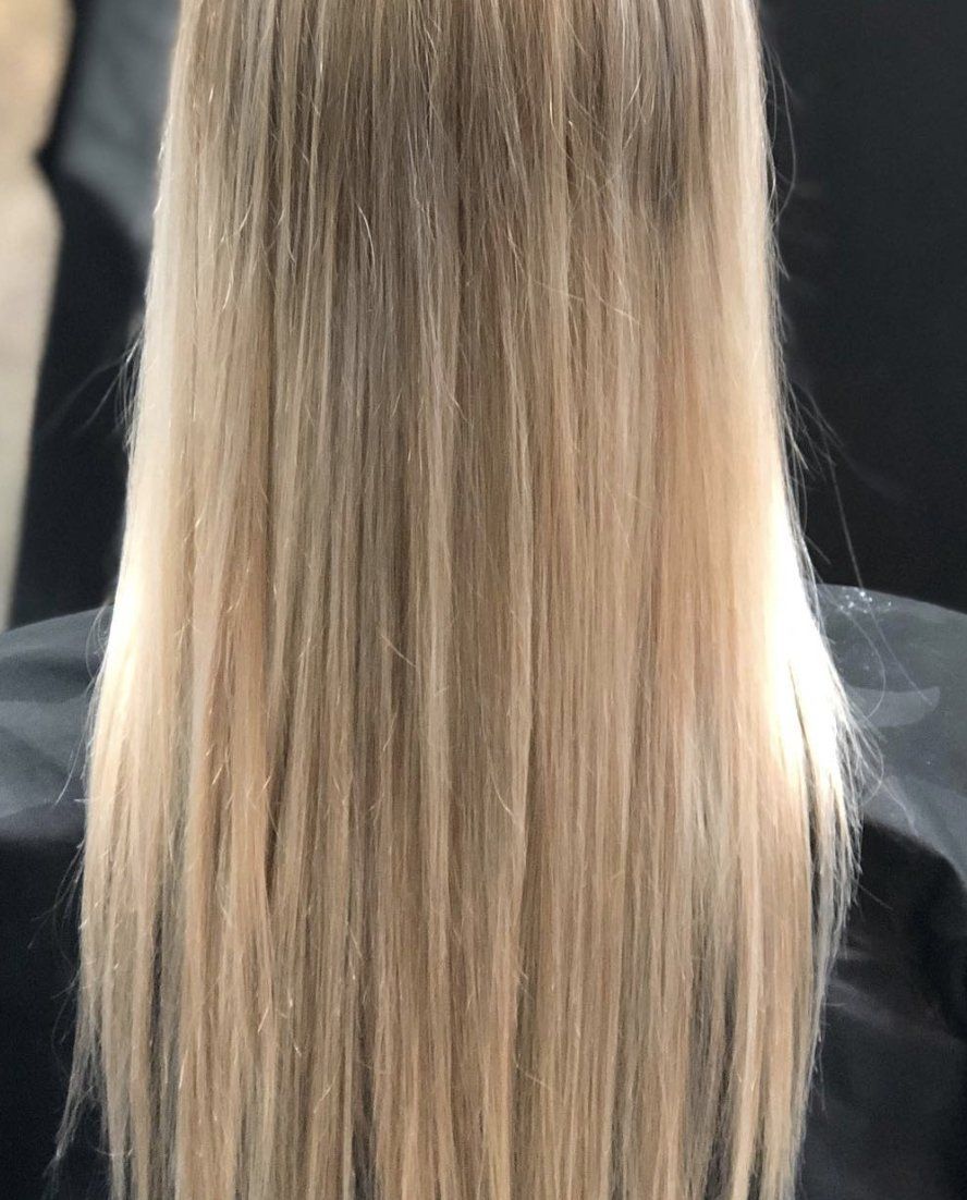 A woman with long blonde hair is sitting in a chair.