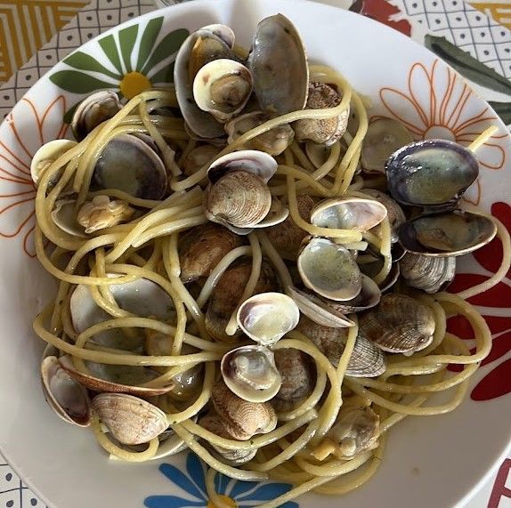 Spaghetti alle vongole: pasta con vongole in salsa cremosa, servita su un piatto floreale.