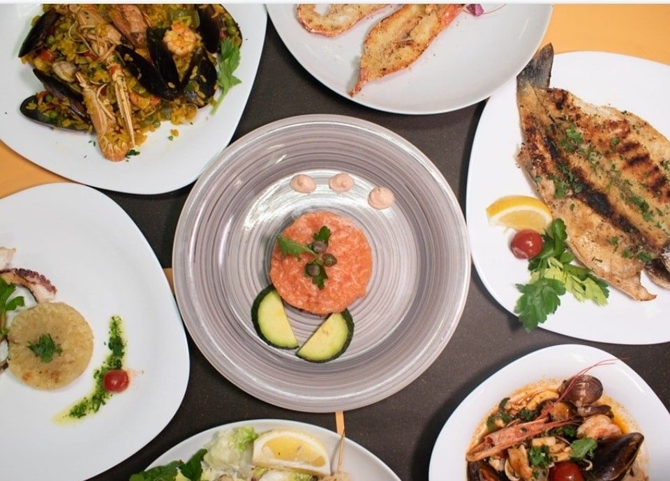 Piatti di vari piatti di pesce su un tavolo, tra cui pesce, cozze e polpo.