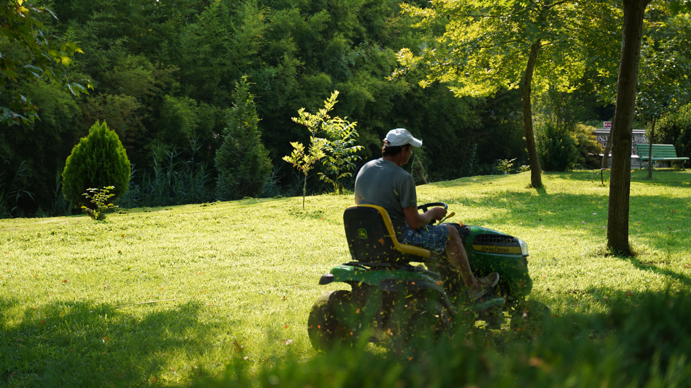 A man is riding a lawn mower in a park.